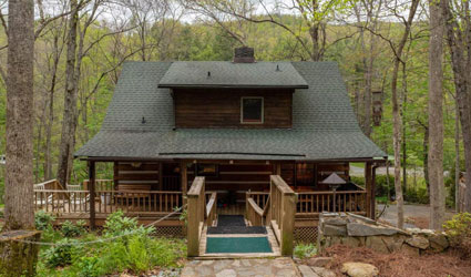 A rustic log cabin with a green roof, perfect for camping and river tubing adventures nearby.