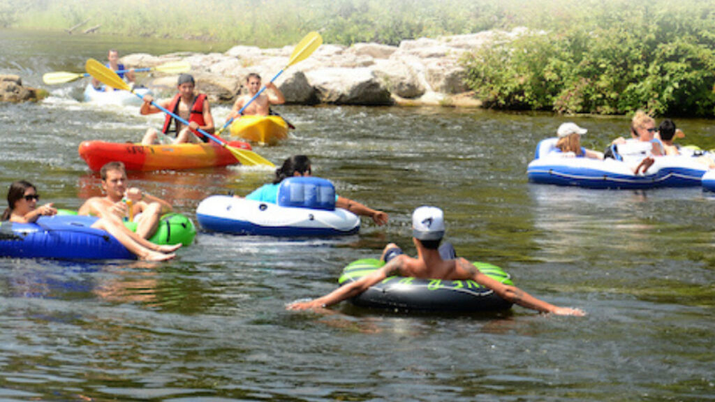 People float down a river in colorful tubes near lush greenery, enjoying Wahoo's Adventures.