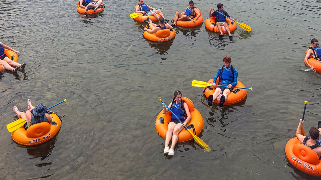 People river tubing on orange tubes with yellow paddles, seen from above at Wahoo's Adventures.