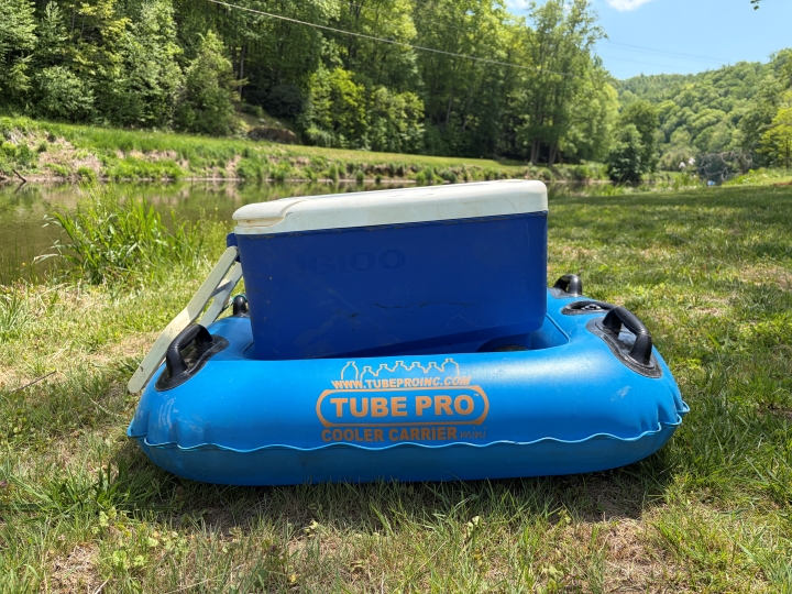 Blue Tube Pro cooler carrier—perfect for bringing food & drinks river tubing beside the grassy bank.