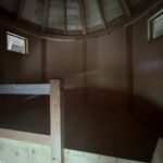 Interior of a wooden Treehouse Cabin near Boone NC with bunk bed, round ceiling, and windows.