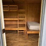 Treehouse Cabins Near Boone NC: Wooden cabin room with bunk beds left, single bed right, from doorway.