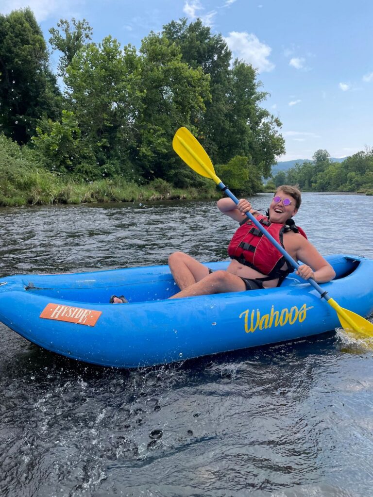 Person paddling a blue Wahoos kayak, enjoying Tubing Rafting & Camping in TN on a scenic river.